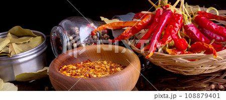 Wooden bowl of chili flakes, bay leaf, black pepper 108879401