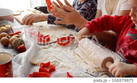 Closeup of family hands rolling dough and cutting cookies and ginger bread for Christmas celebrations. Winter holidays, celebrations and party. 108879975