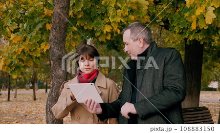 Man and woman employees of company discussing work related matters in park Man and woman employees of company discussing work related matters in park 108883150