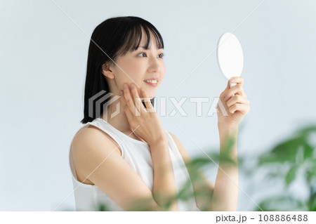 鏡で肌をチェックする白い服の若い女性 鏡で肌をチェックする白い服の若い女性 108886488