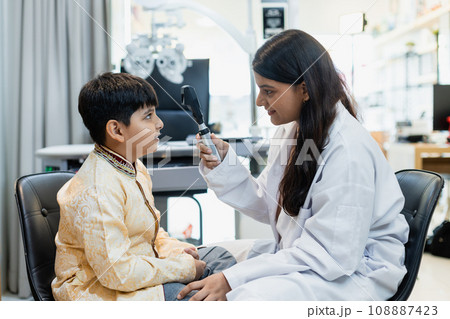 Indian child boy with women eye specialist examining eyesight modern ophthalmology. Indian child boy with women eye specialist examining eyesight modern ophthalmology. 108887423