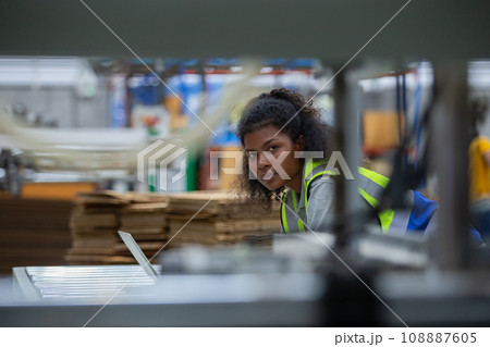 Staff worker woman american african using laptop check quality and quantity stock paper product. Staff worker woman american african using laptop check quality and quantity stock paper product. 108887605