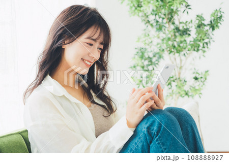 ソファに座ってスマホを使う女性 ソファに座ってスマホを使う女性 108888927