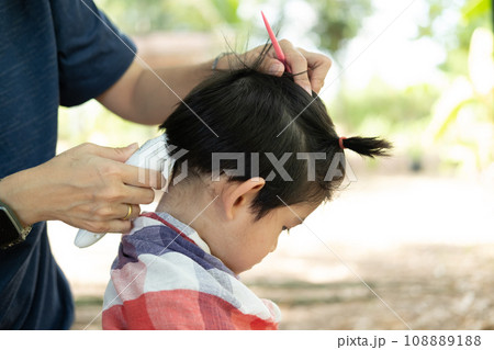 Barber cutting hair of an Asian boy In an open space filled with trees. Barber cutting hair of an Asian boy In an open space filled with trees. 108889188