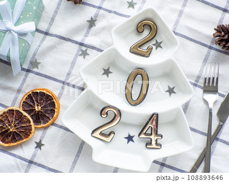 Empty christmas tree shaped white plate with 2024 on towel background 108893646