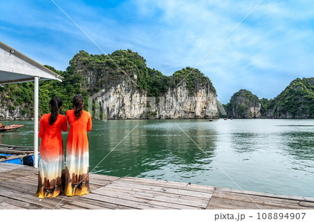 ベトナム 奇岩が続くハロン湾のパールファームで観光客の船を待つ赤いアオザイの女性 ベトナム 奇岩が続くハロン湾のパールファームで観光客の船を待つ赤いアオザイの女性 108894907