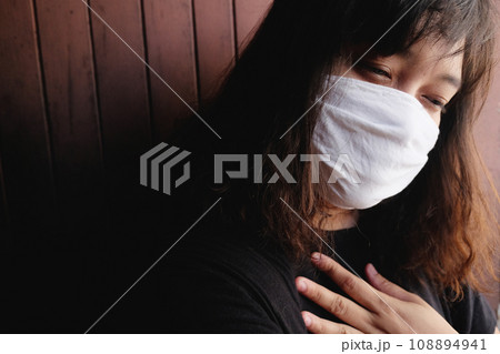 Asian Thai woman wearing a white cloth mask for prevent the Covid-19 or Corona virus and Air Pollution Value Pm 2.5 in Thailand. She is suffocating in Respiratory system. Health and illness concept 108894941