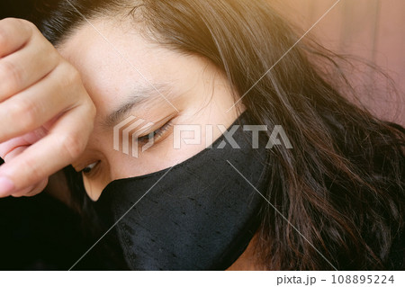Asian Thai woman wearing a black cloth mask for prevent the Covid-19 or Corona virus and Epidemic disease at Thailand and around the world. She is serious and headache. Health and illness concept Asian Thai woman wearing a black cloth mask for prevent the Covid-19 or Corona virus and Epidemic disease at Thailand and around the world. She is serious and headache. Health and illness concept 108895224