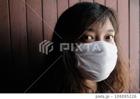 Asian Thai woman wearing a white cloth mask for prevent the Covid-19 or Corona virus and Epidemic disease at Thailand and around the world. Air pollution pm2.5. Health and illness concept Asian Thai woman wearing a white cloth mask for prevent the Covid-19 or Corona virus and Epidemic disease at Thailand and around the world. Air pollution pm2.5. Health and illness concept 108895226