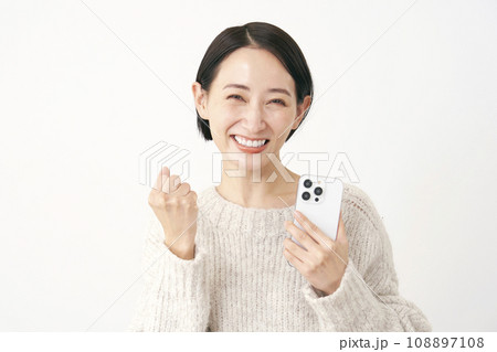 スマホを持ってガッツポーズをするミドルエイジの女性　白背景 108897108