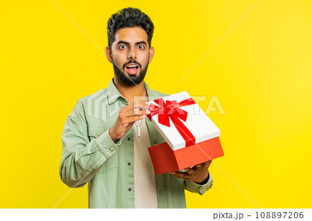 Man opening birthday gift box with red ribbon, receiving great present surprise, celebrating 108897206