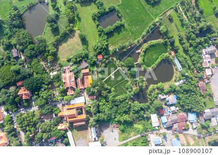 Drone view of Sufficiency Economy, Land full of agricultural activities with green rice fields, big ponds, and trees. Small houses and temple close by a pond. Drone view of Sufficiency Economy, Land full of agricultural activities with green rice fields, big ponds, and trees. Small houses and temple close by a pond. 108900107