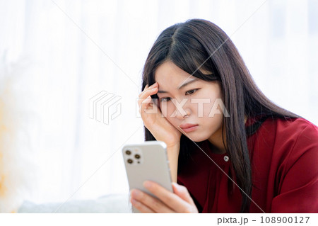 悩む女性　スマホ 108900127