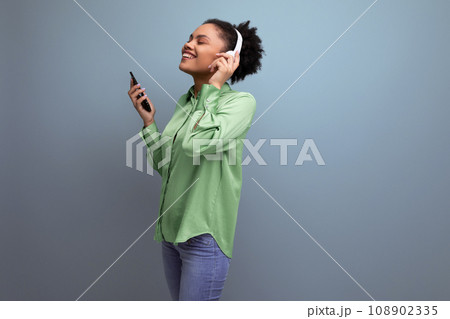 young energetic music lover latin business lady in green blouse listening to music with headphones young energetic music lover latin business lady in green blouse listening to music with headphones 108902335