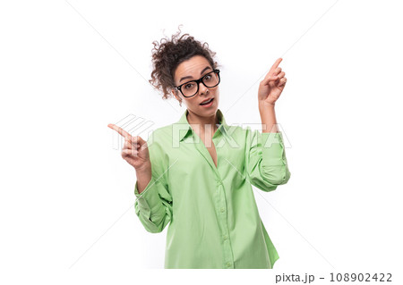 pretty young brunette curly woman in glasses is dressed in a green shirt on a white background with 108902422