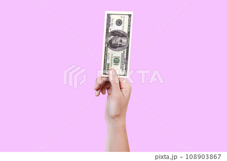 Close up woman hand hold money 100 dollar bill. Money in a hand isolated on violet background 108903867