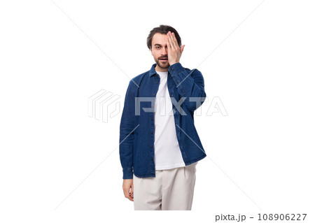 young european brunette man with a cool hairstyle is dressed in a blue denim shirt over a t-shirt young european brunette man with a cool hairstyle is dressed in a blue denim shirt over a t-shirt 108906227