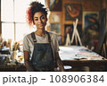 Portrait of young passionate artist in her mid-20s, wearing a worn-out denim apron 108906384