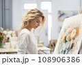 Blonde female artist, passionately engaged with a large canvas 108906386