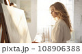 Blonde female artist, passionately engaged with a large canvas 108906388