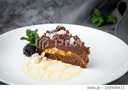 gluten free chocolate cake with nuts, berries and mint on a white plate gluten free chocolate cake with nuts, berries and mint on a white plate 108906411