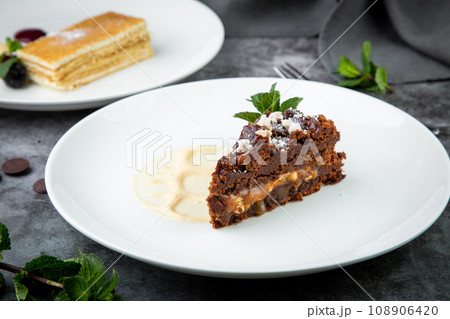 gluten free chocolate cake with nuts, berries and mint on a white plate gluten free chocolate cake with nuts, berries and mint on a white plate 108906420