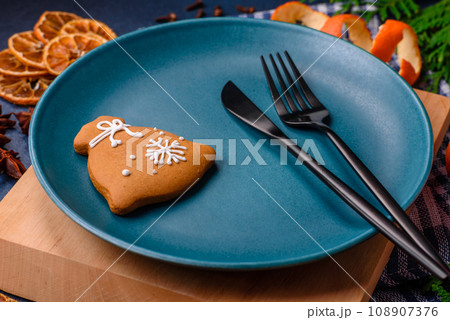 Beautiful festive Christmas composition of an empty plate, tangerine and gingerbreads Beautiful festive Christmas composition of an empty plate, tangerine and gingerbreads 108907376