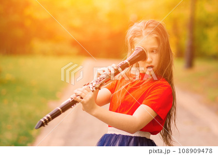 Young attractive girl playing clarinet, ebony in fall park 108909478