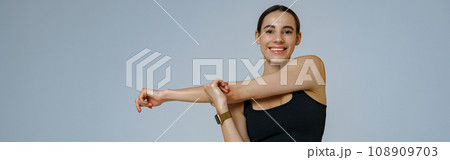 Close up of smiling woman doing warm-up before training session in gym on studio background 108909703