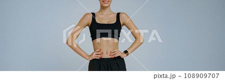 Portrait of smiling fitness woman wearing sportswear looking at camera on studio background 108909707