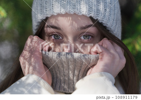 Crop shot teenager girl pulling collar of sweater up to eyes, hiding face from cold winter weather 108911179
