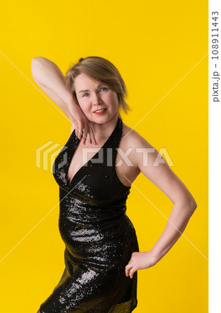 Portrait of curvy mature blonde female in evening gown with spangles, posing, looking at camera Portrait of curvy mature blonde female in evening gown with spangles, posing, looking at camera 108911443