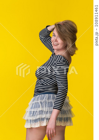 Curvy mature blondie in mini skirt and long sleeve shirt looking at camera over shoulder with smile 108911461