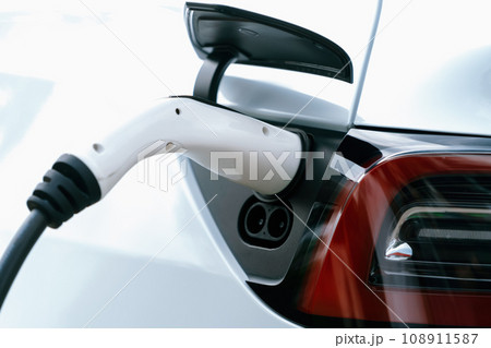 Closeup EV charger plug handle attached to electric vehicle port. Synchronos 108911587