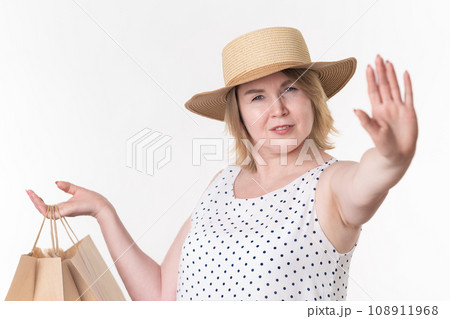 Woman shopper in white dress put hand out in front of palm of her hand and making stop sign 108911968
