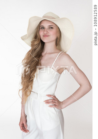 Portrait of model wearing her new clothes, to dress up straw hat, white cupped corset top, trousers 108912589