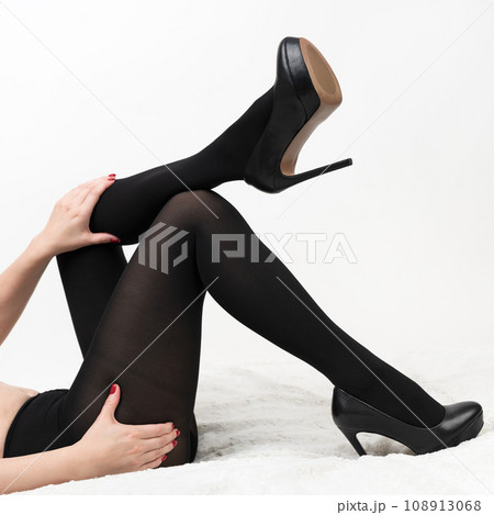 Woman in tights and high heel lying, legs bent at knees, one leg lies on knee, hands on hip and knee 108913068