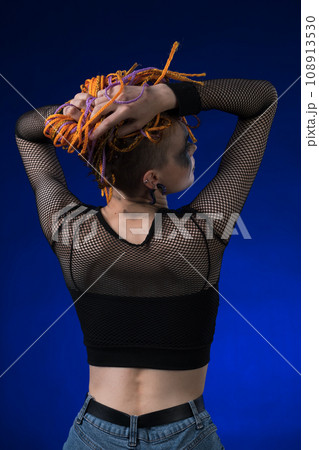 Rear view of young woman with colored braids hairdo and horror black stage make-up painted on face Rear view of young woman with colored braids hairdo and horror black stage make-up painted on face 108913530