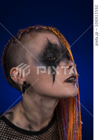 Dramatic portrait of informal woman with horror stage makeup on face, colored dreadlocks hairstyle 108913592