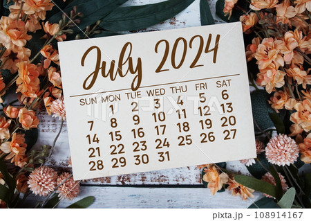 July 2024 monthly calendar with flower bouquet decoration  on wooden background 108914167