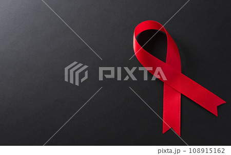 Closeup red ribbon HIV, world AIDS day awareness ribbon on black background. Healthcare and medicine concept. 108915162