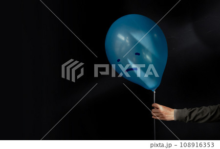 Mental Health Disorder Concept. a Stressed, Anxiety, Depressed Person Holding a Blue Balloon with a Sadness Face from the Dark , Negative Emotion and Feeling. Moody. Dark tone 108916353