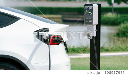EV electric car recharge battery at parking lot in green city park. Expedient 108917923