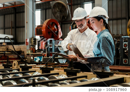 Factory engineer with assistant using laptop inspect factory. Exemplifying 108917960