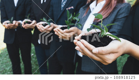 Business people holding plant or sprout together in unity as CSR commitment.Gyre 108918125