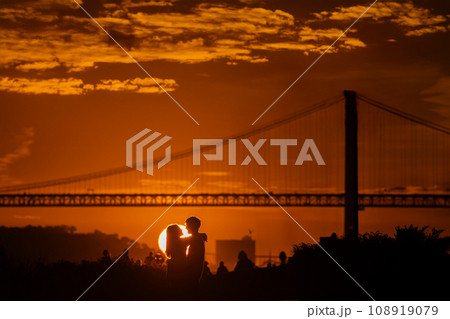 Sunset Romance: A Couple's Kiss by the Bridge at Dusk Sunset Romance: A Couple's Kiss by the Bridge at Dusk 108919079