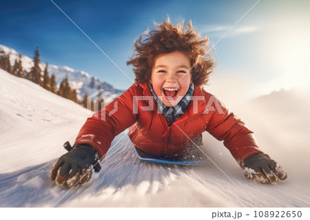 Cheerful kid sliding downhill in winter sunshine. AI content 108922650