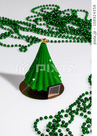 Christmas tree shaped pastry and green beads on white Christmas tree shaped pastry and green beads on white 108924356