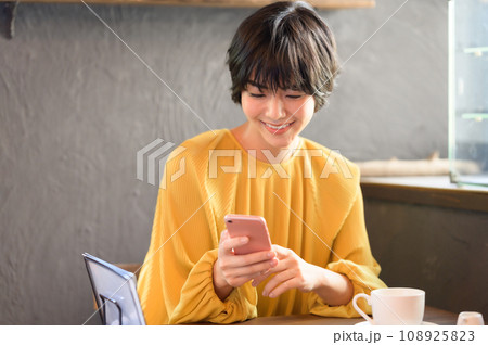 カフェでスマホを手に取る女性　撮影協力「洋菓子店　sentiment」 108925823