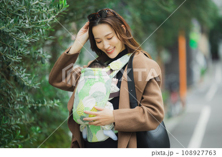 抱っこ紐で赤ちゃんと外出するママ 108927763
